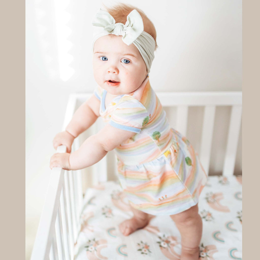 Anise & Ava baby onesie dress front in genderless Sunray Rainbow print front with contrast ribbing and envelop neck for easy wearing. Made to twin with siblings tee or dress