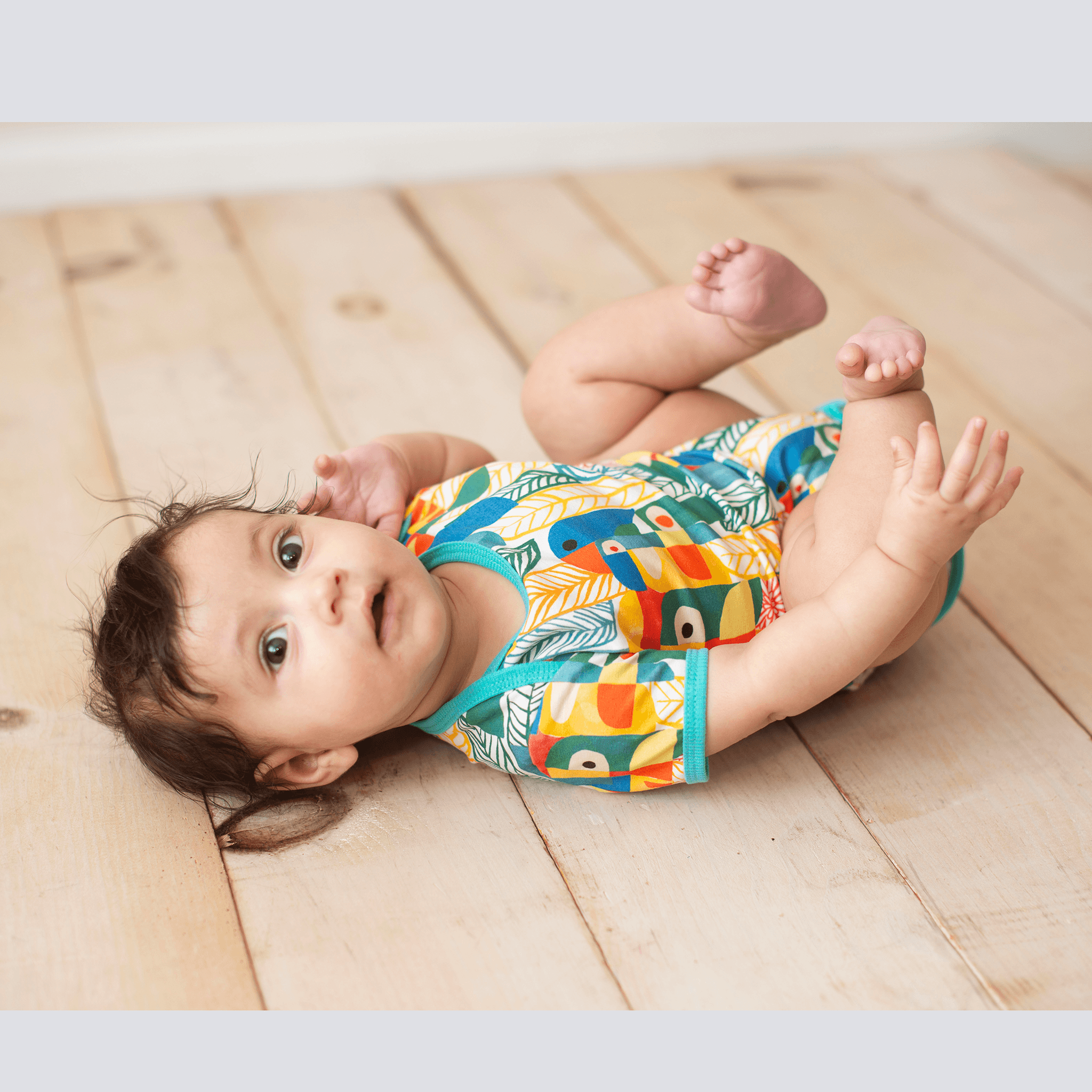 Anise & Ava's gender neutral colorful exclusive artwork designed and drawn in house. Baby snap body in Parrots print made to match siblings' styles in dresses & shirts for all boys & girls. 