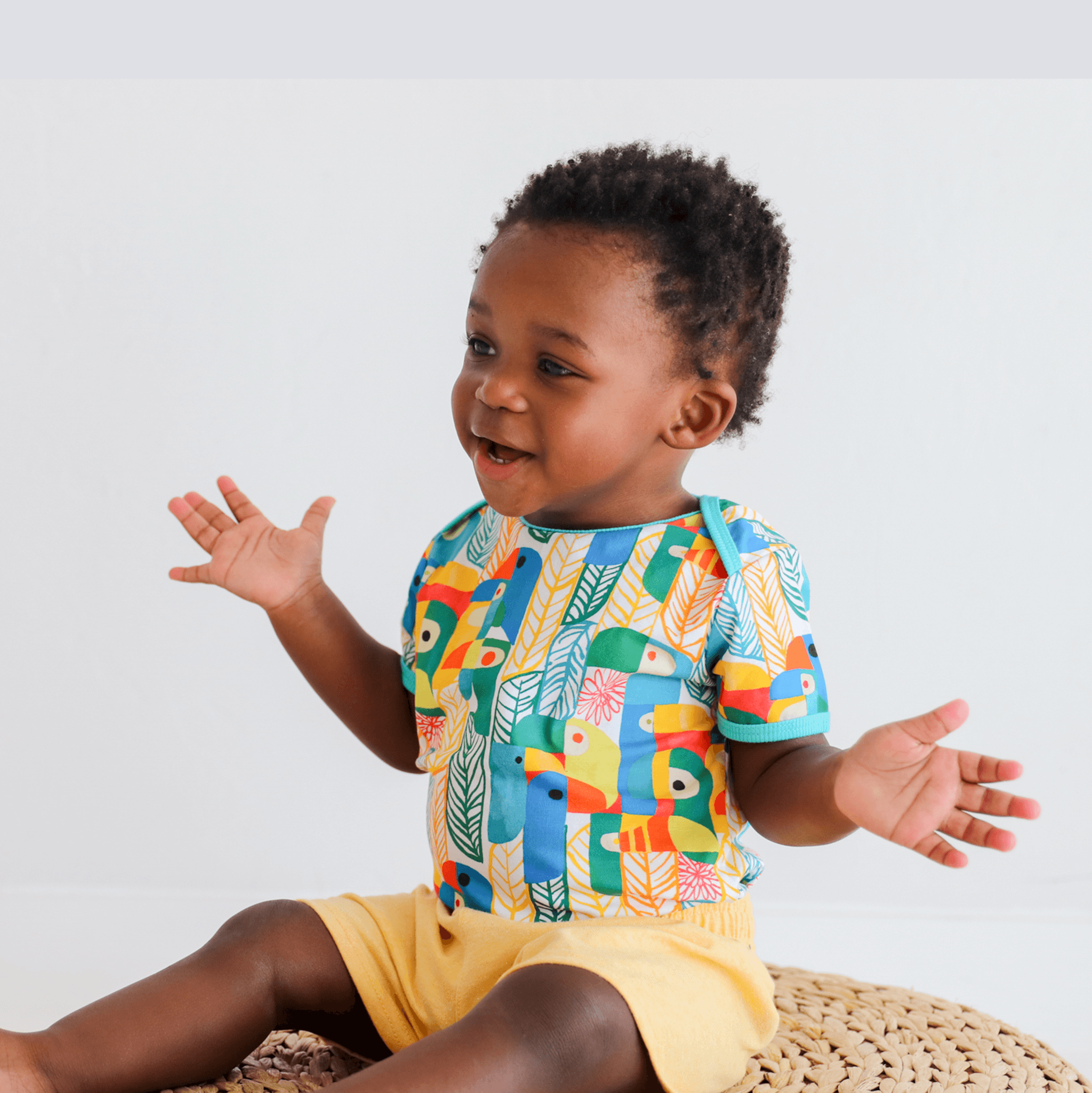 Anise & Ava's gender neutral colorful exclusive artwork designed and drawn in house. Baby snap body in Parrots print made to match siblings' styles in dresses & shirts for all boys & girls. 