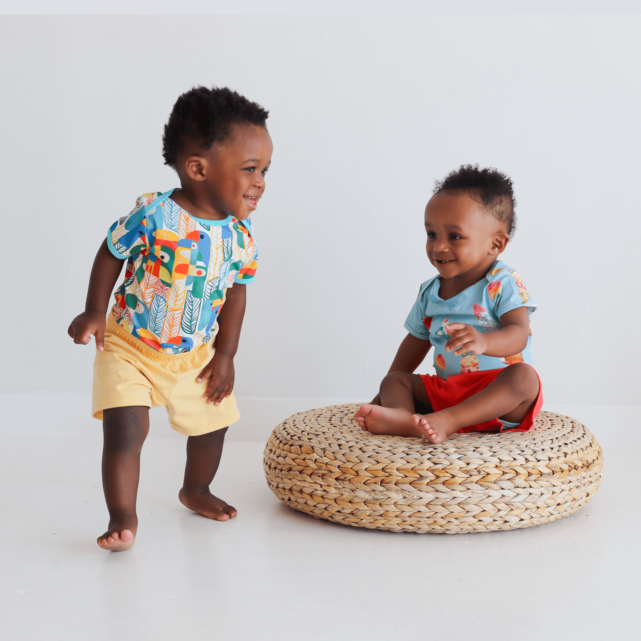 Anise & Ava's gender neutral colorful exclusive artwork designed and drawn in house. Baby snap body in Parrots print made to match siblings' styles in dresses & shirts for all boys & girls. 