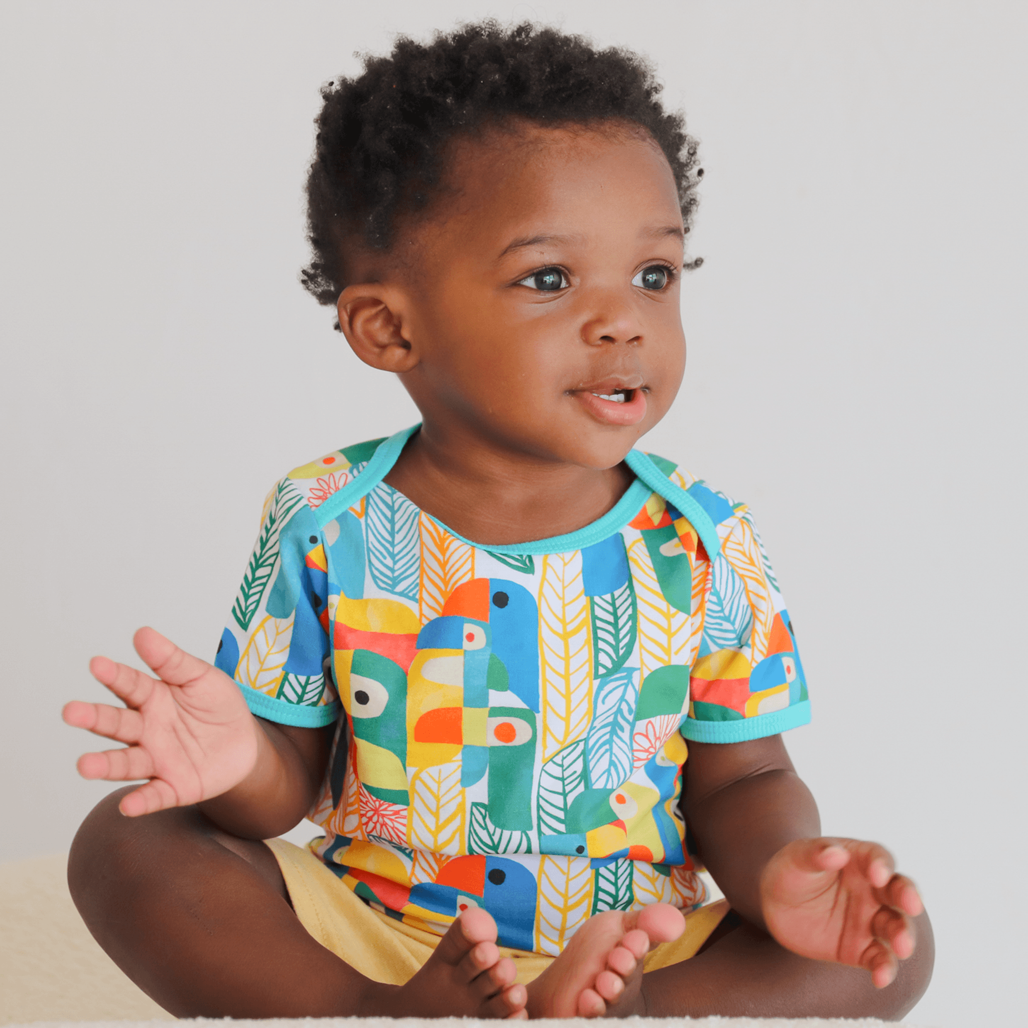 Anise & Ava's gender neutral colorful exclusive artwork designed and drawn in house. Baby snap body in Parrots print made to match siblings' styles in dresses & shirts for all boys & girls. 